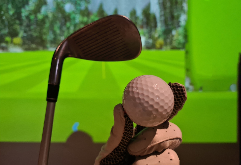 Golfer,in,glove,holds,golf,ball,and,club,indoors.,playing