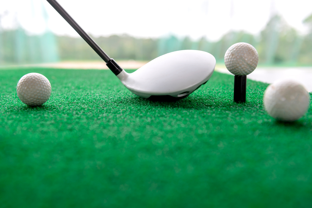 Golf,club,and,balls,on,a,synthetic,grass,mat,at